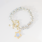 As worn by Jo Good, Ana Verdun chain bracelet with a T-bar clasp and a dangling star charm. The charm features a textured silver centre with a gold beaded border, set against a clean white background.