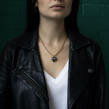 Person wearing a black leather jacket and white shirt with a gold necklace featuring the Valentina Heart Locket.